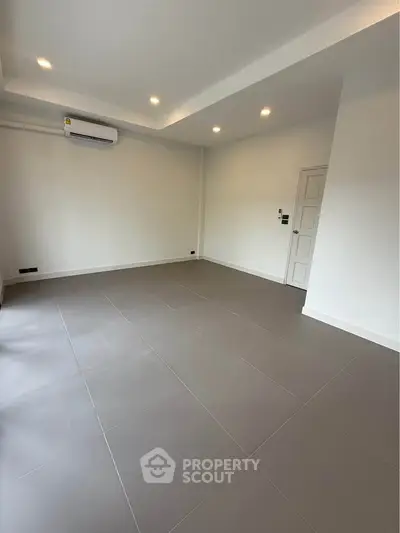 Spacious empty room with modern tile flooring and air conditioning unit.