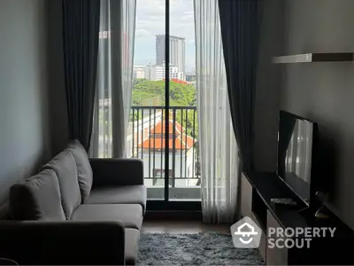 Modern living room with balcony and city view, featuring cozy sofa and entertainment unit.