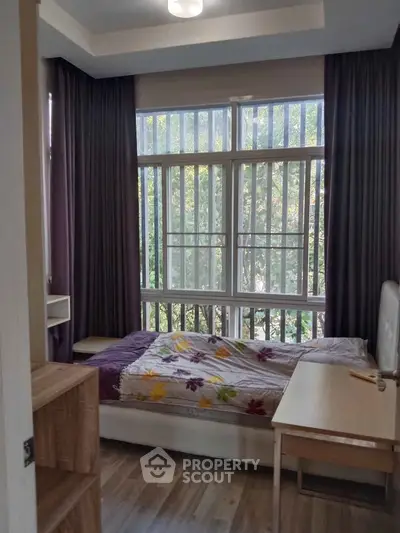 Cozy bedroom with large windows and natural light, featuring modern decor and a serene view.
