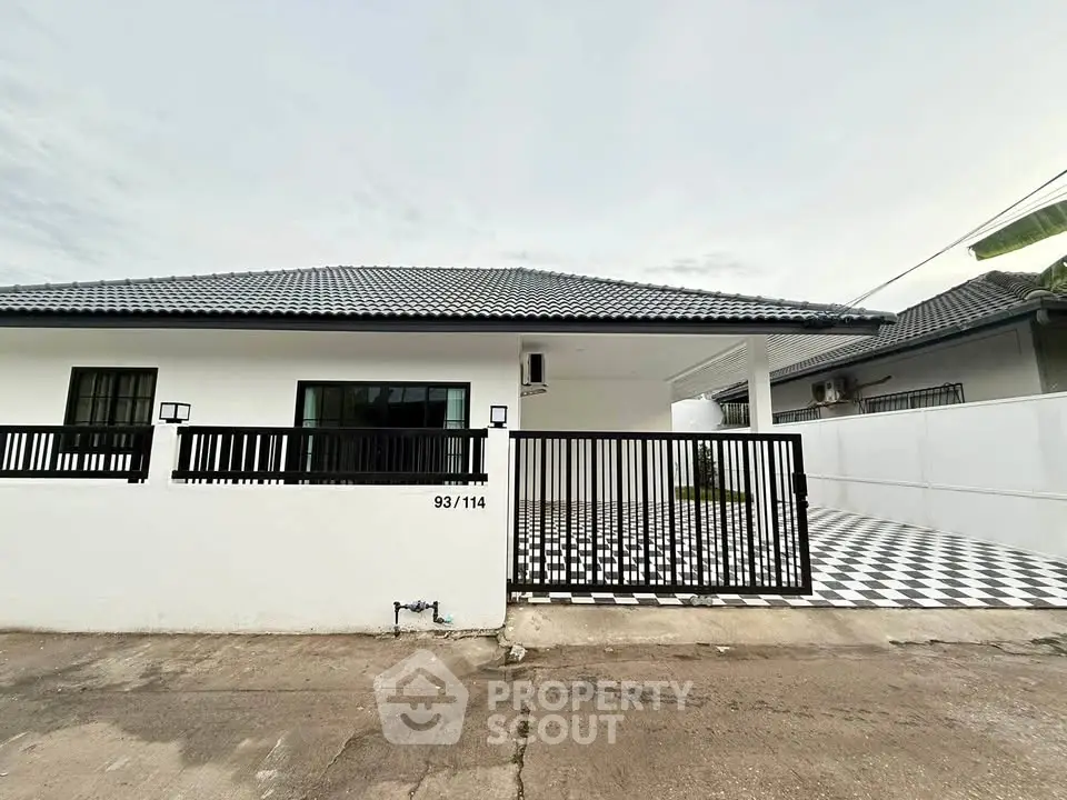 Modern single-story house with gated entrance and checkered driveway