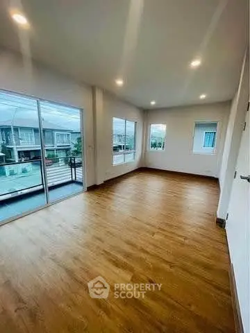 Spacious empty room with wooden flooring and large windows in modern home