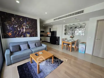 Modern open-plan living room with kitchen, featuring stylish decor and ample natural light.