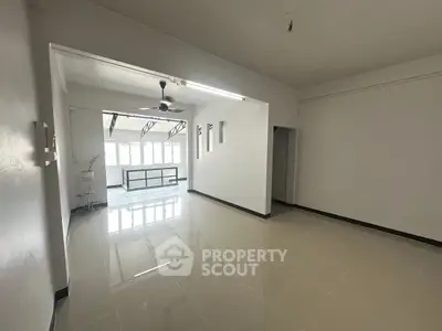 Spacious unfurnished living room with large windows and ceiling fan