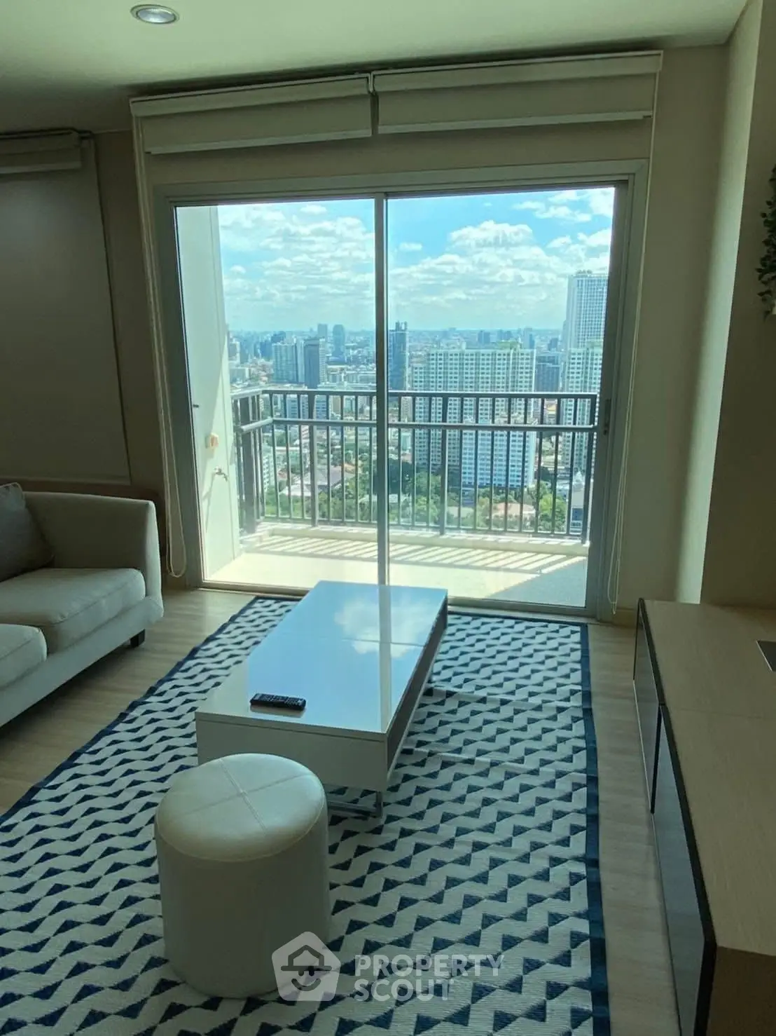 Modern living room with stunning city view from balcony, featuring stylish furniture and natural light.