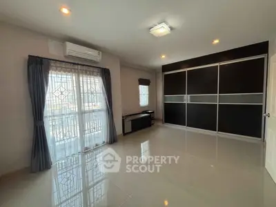 Spacious modern living room with large windows and sleek black storage unit.