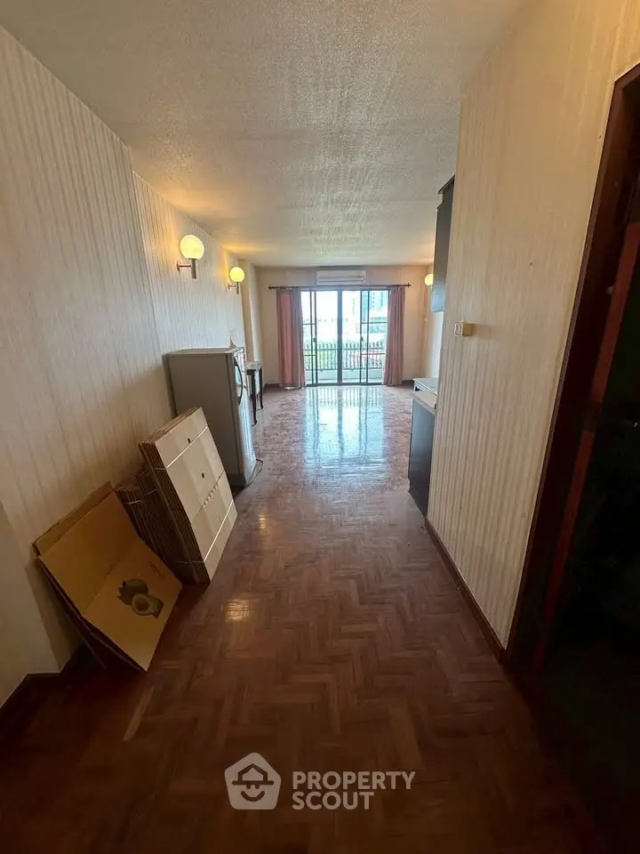Spacious hallway with parquet flooring leading to a bright balcony view.