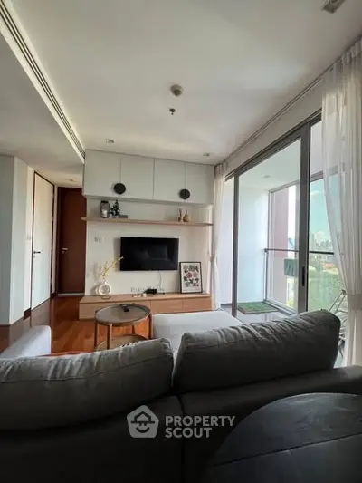 Modern living room with balcony view, featuring sleek furniture and natural light.