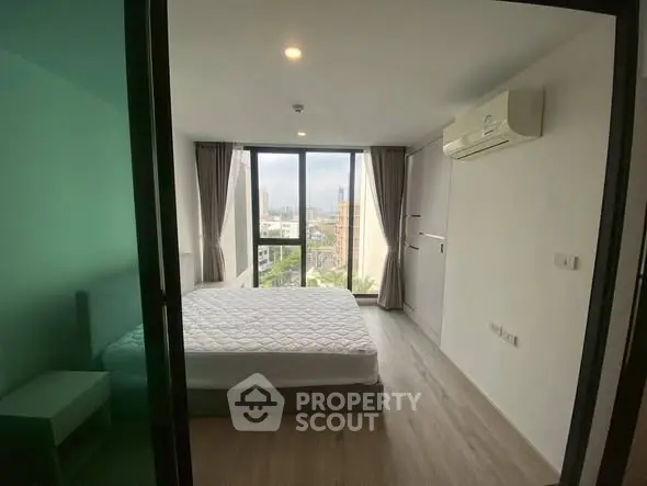 Modern bedroom with large windows and city view, featuring minimalist design and air conditioning.