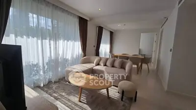 Spacious modern living room with elegant furniture and large windows offering natural light.