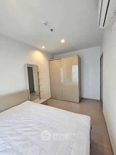 Modern bedroom with sleek wardrobe and air conditioning in a stylish apartment.