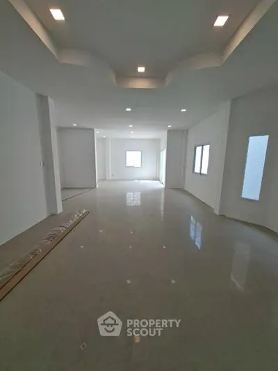 Spacious modern living room with elegant ceiling design and large windows for natural light.