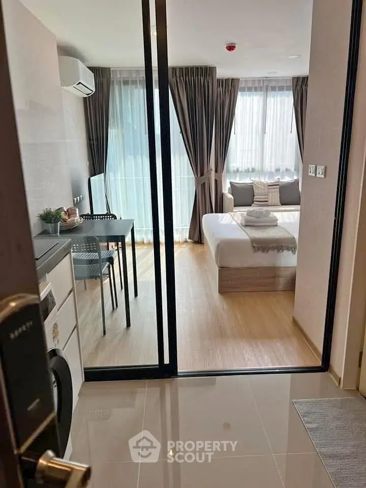 Modern studio apartment with glass partition, featuring a cozy bedroom and compact living area.