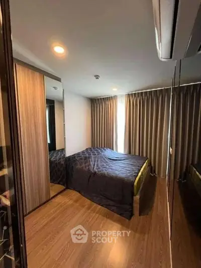 Modern bedroom with wooden flooring and large mirrored wardrobe in a cozy apartment.