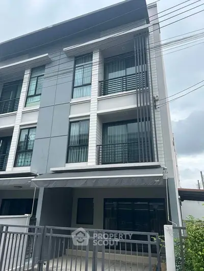 Modern three-story townhouse with sleek design and large windows in a suburban neighborhood.