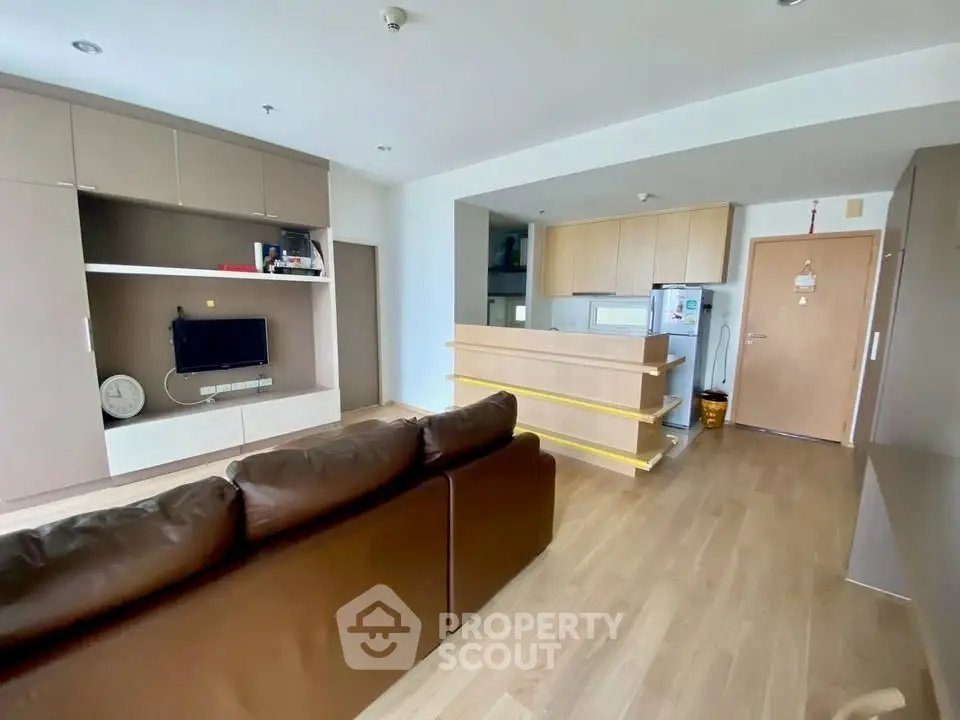 Modern open-layout living room with sleek kitchen and cozy brown sofa