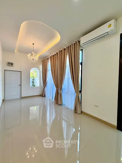 Elegant living room with chandelier and large windows, featuring modern air conditioning.
