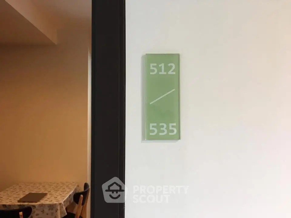 Interior hallway with room number sign and dining table setup.