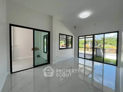 Spacious modern living room with large windows and glossy tile flooring, offering a bright and airy ambiance.