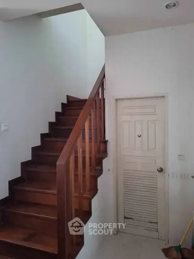 Charming wooden staircase with white walls and a small storage door underneath.