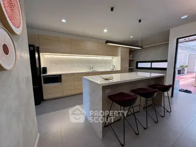 Modern kitchen with marble island and sleek cabinetry, featuring open layout and stylish bar stools.