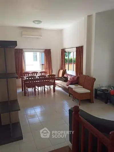 Spacious living room with dining area and natural light, perfect for family gatherings.