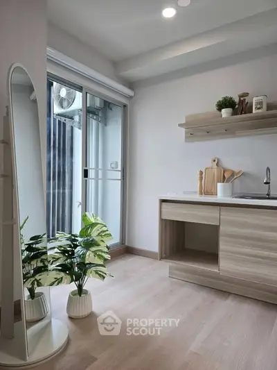 Modern kitchen with open layout and sleek design, featuring a large mirror and potted plants for a fresh ambiance.