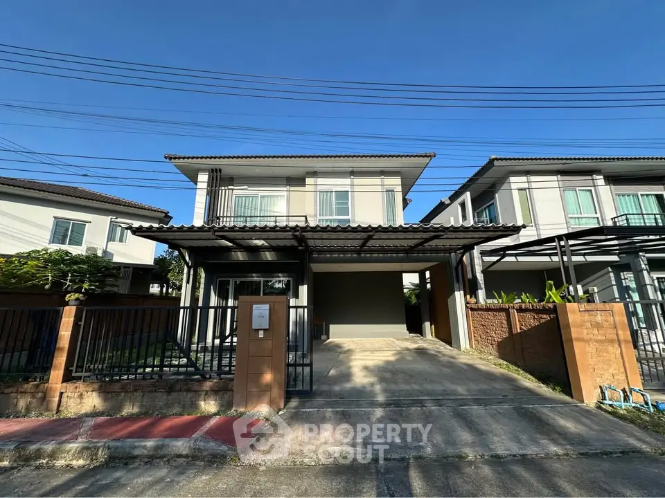 Modern two-story house with driveway and gated entrance in a suburban neighborhood.