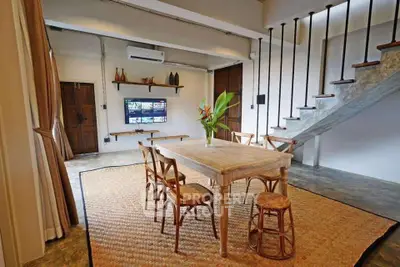 Charming open-plan living area with rustic dining set and modern staircase, perfect for stylish urban living.