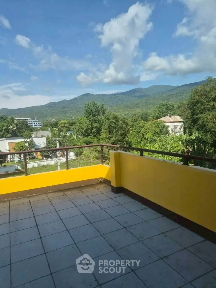 Spacious balcony with stunning mountain views and vibrant yellow railing, perfect for relaxation.