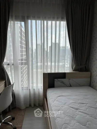 Cozy bedroom with city view, featuring a modern bed and desk setup, ideal for urban living.