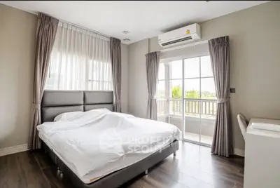 Spacious bedroom with large windows and balcony access, featuring modern decor and natural light.