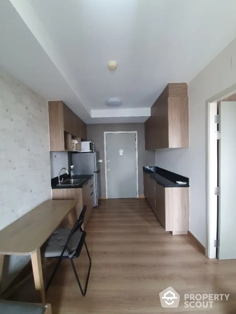 Modern kitchen with wooden cabinets and sleek countertops in a compact apartment.