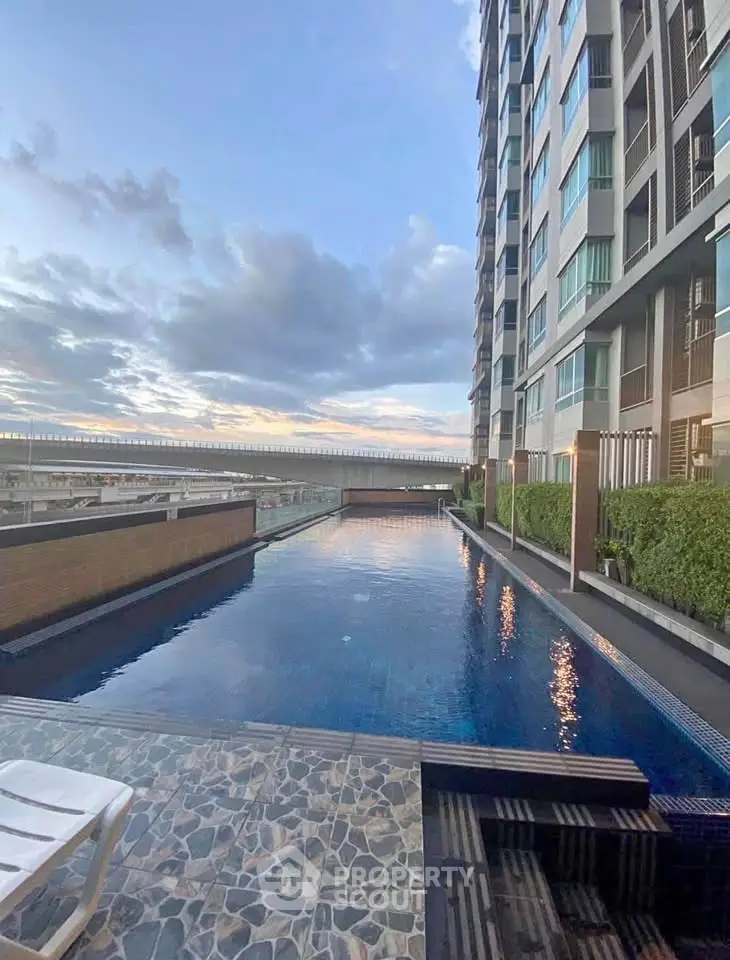 Luxurious high-rise building with stunning rooftop pool and panoramic city views at sunset.
