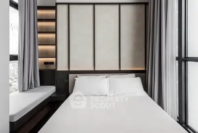 Modern bedroom with sleek design and large windows offering city views.