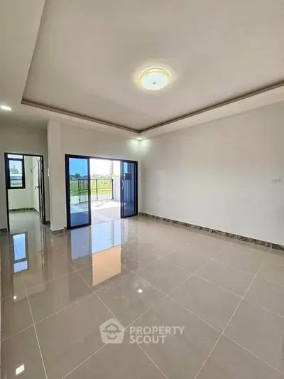 Spacious living room with glossy tiled floors and large sliding doors to balcony.