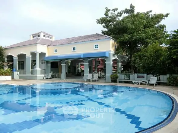Luxurious residential pool area with elegant clubhouse and lush greenery.