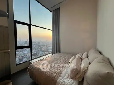 Luxurious bedroom with stunning city view through large windows at sunset.