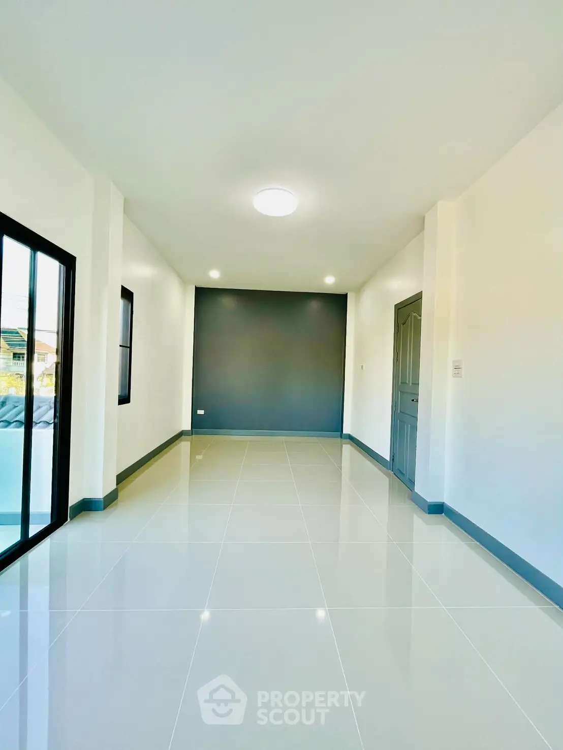 Spacious and bright interior hallway with modern tile flooring and large windows.