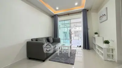Modern living room with sleek gray sofa, glass coffee table, and balcony view in stylish apartment.
