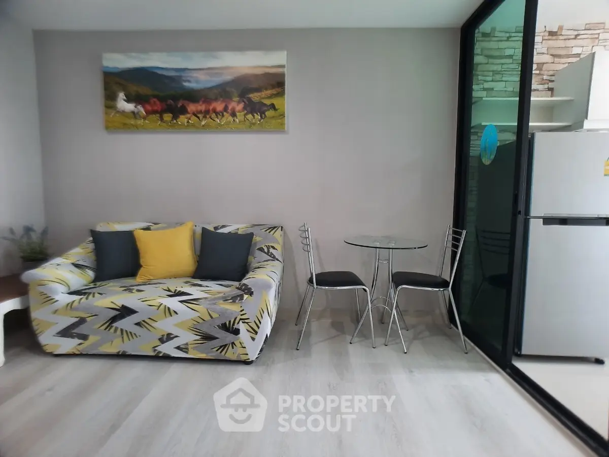 Modern living room with stylish sofa, glass table, and sleek kitchen area.