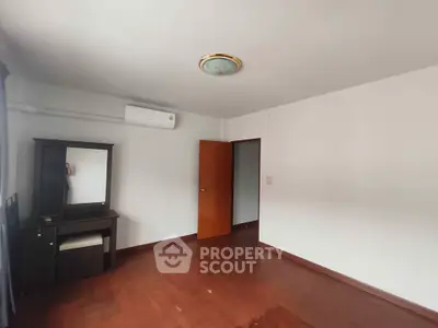 Spacious bedroom with wooden flooring and air conditioning in modern apartment.