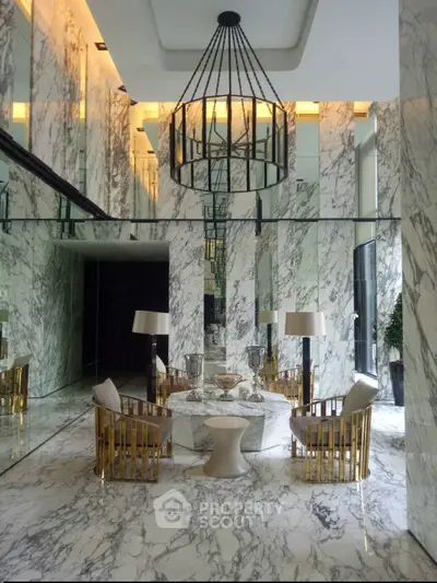Luxurious marble lobby with elegant chandelier and gold-accented furniture, perfect for upscale living.
