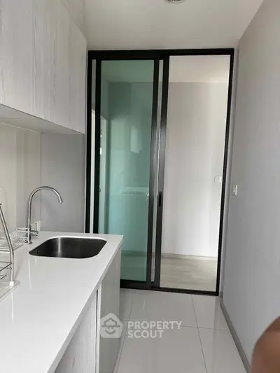 Modern kitchen with sleek design and sliding glass door, featuring a minimalist aesthetic and high-quality finishes.
