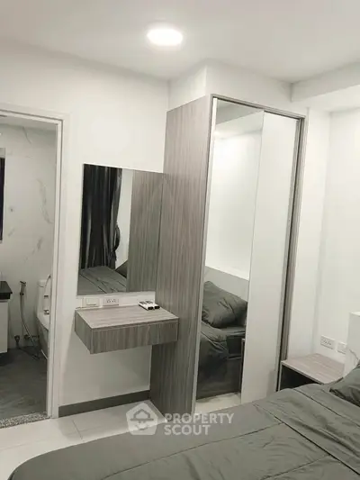 Modern bedroom with sleek design and mirrored wardrobe in a contemporary apartment.
