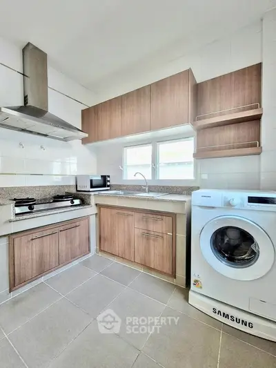 Modern kitchen with wooden cabinets, gas stove, and washing machine