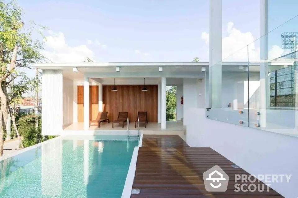 Modern villa with infinity pool and sun loungers, featuring sleek architecture and serene outdoor space.