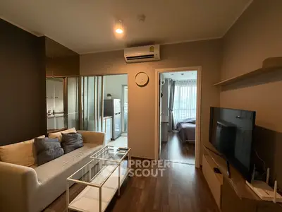Modern living room with sleek design, featuring a cozy sofa, glass coffee table, and wall-mounted TV.