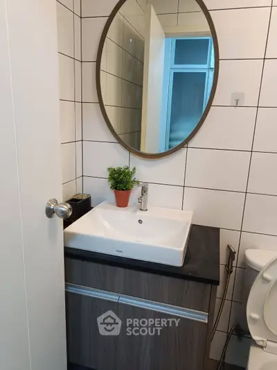 Modern bathroom with sleek sink and round mirror, stylish and functional design.