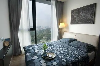 Modern bedroom with large window offering stunning city view and elegant decor.