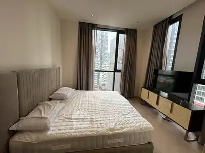 Luxurious bedroom with city view, featuring a plush bed and modern TV stand, perfect for urban living.